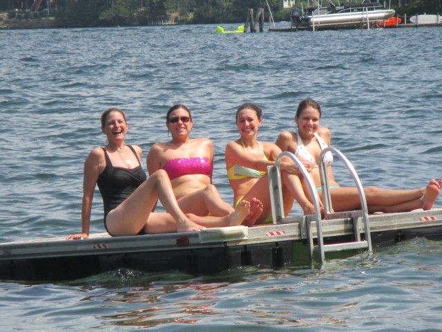 A group of girls sitting on a bench by the water